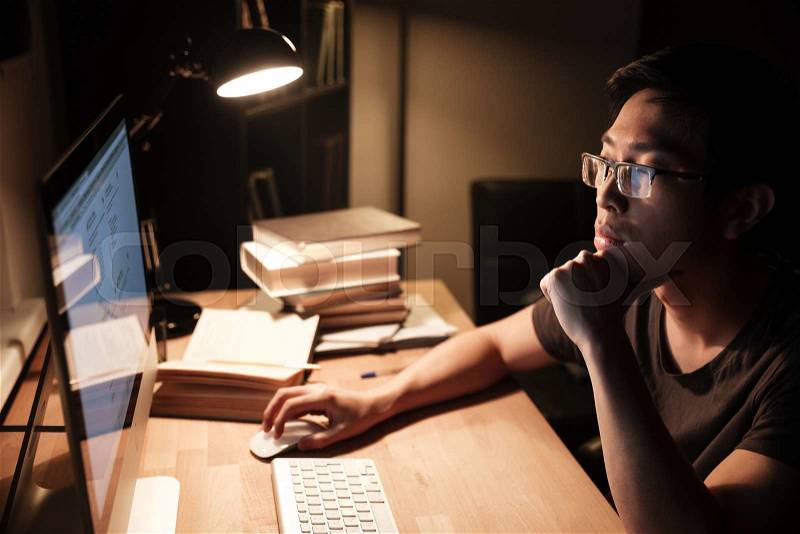 Pensive man working with computer and thinking in the evening, stock photo
