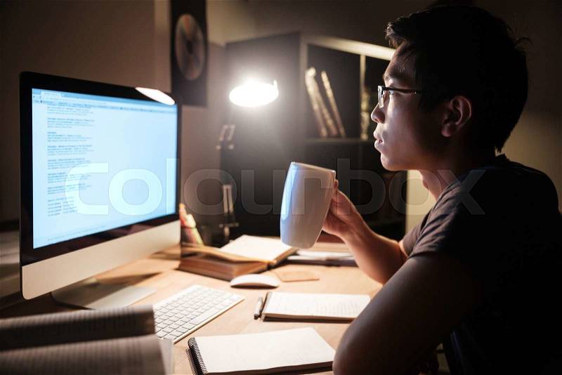 Handsome man studying with computer and drinking tea, stock photo