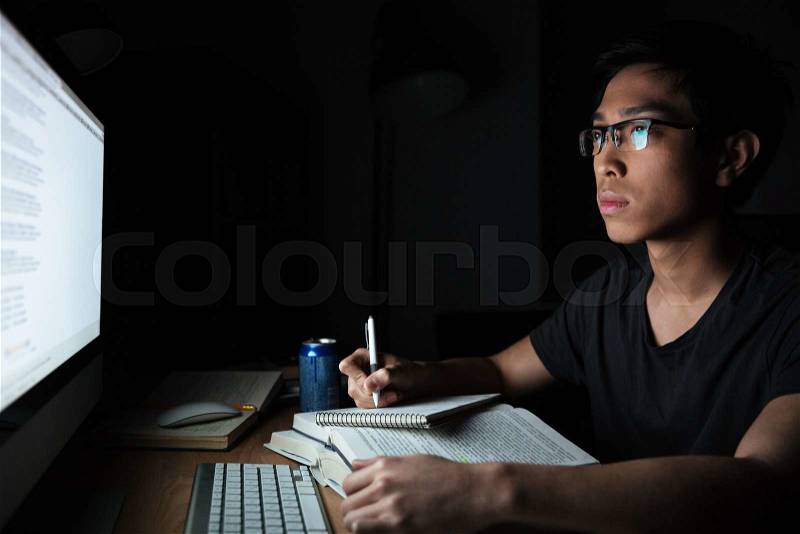 Man writing in notepad and using computer, stock photo