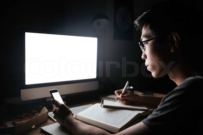 Using blank screen mobile phone and computer and writing notes in notepad , stock photo