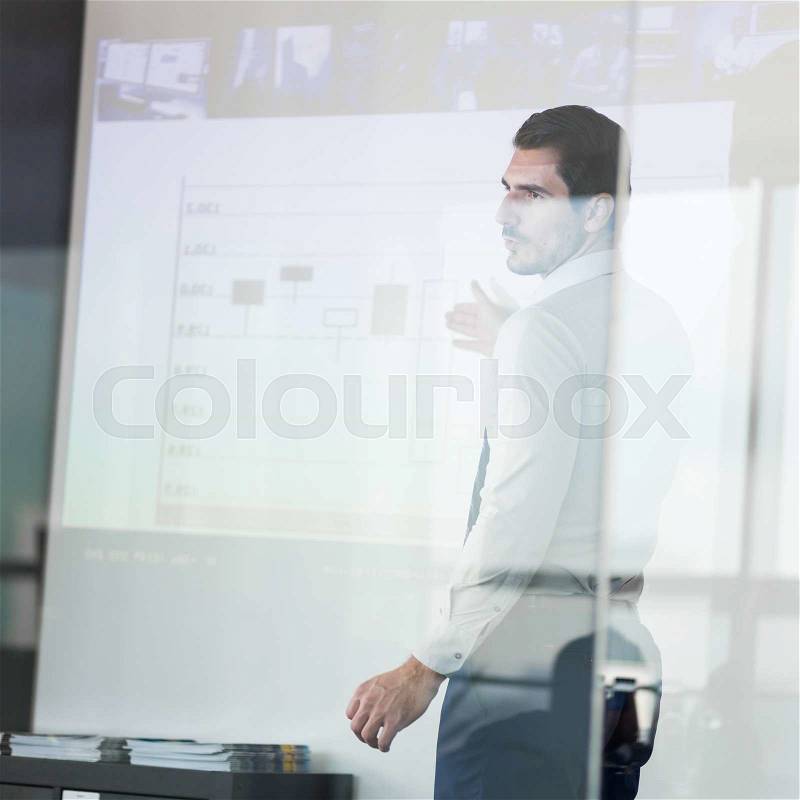 Business man making a presentation in front of whiteboard. View through glass, stock photo