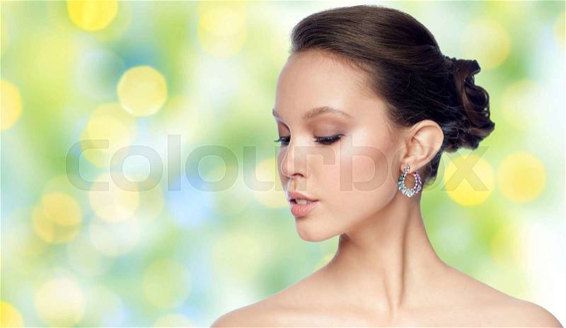 Beauty, jewelry, accessories, people and luxury concept - close up of beautiful asian woman face with earring over summer green lights background, stock photo