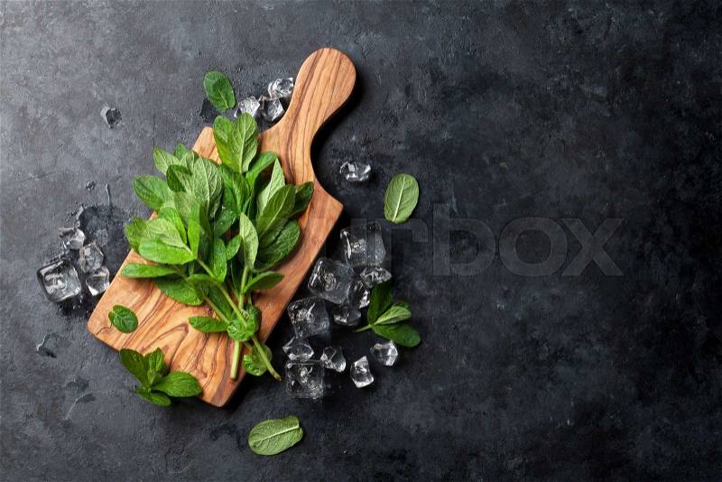 Fresh garden mint and ice on stone table. Top view with copy space, stock photo