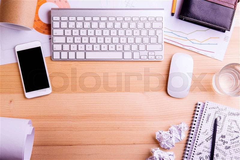 Desk with gadgets and office supplies. Computer keyboard, smart phone and stationery around the workplace. Flat lay. Studio shot on wooden background. Copy space, stock photo