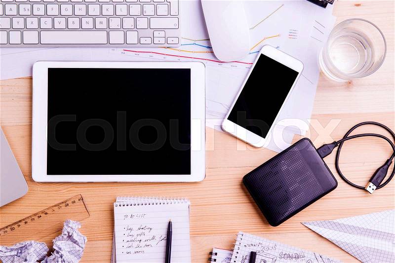 Desk with gadgets, office supplies and chart graph. Tablet, smart phone and stationery around the workplace. Flat lay. Studio shot on wooden background, stock photo