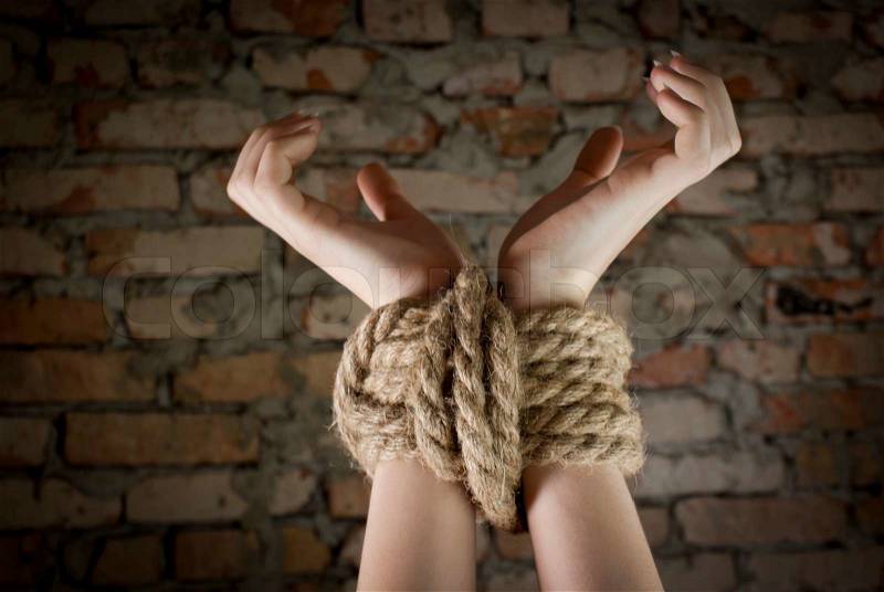 Hands tied up with rope, stock photo