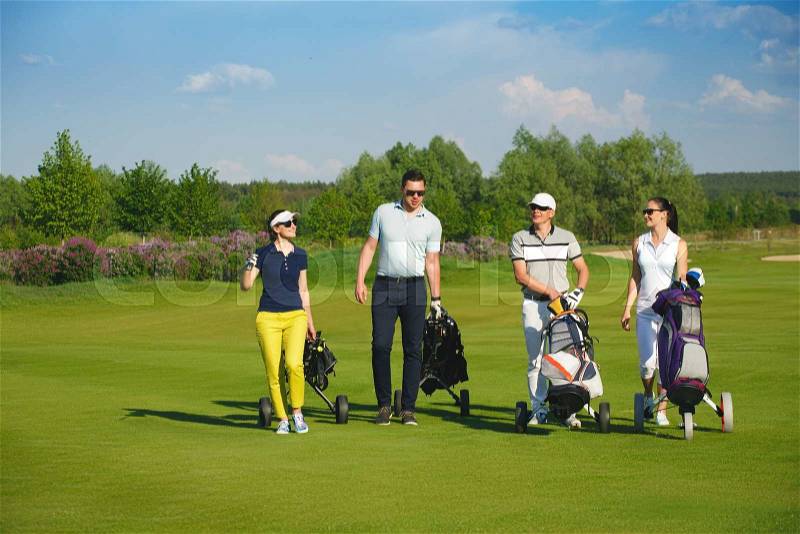 Four friends golfers walking on golf course at sunny day, stock photo