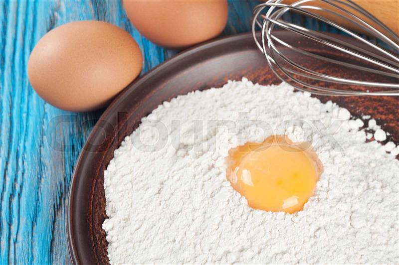 Eggs, egg yolk and flour on a blue wooden background, stock photo