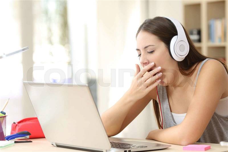 Beautiful bored and tired somnolent student yawning in the morning in a desk at home, stock photo