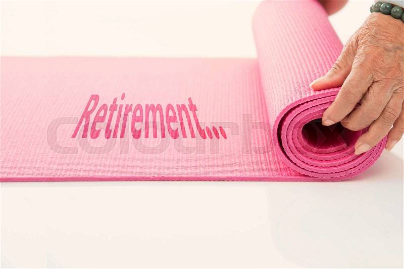 Senior hand\'s rolling pink yoga mat on white with message retirement, stock photo