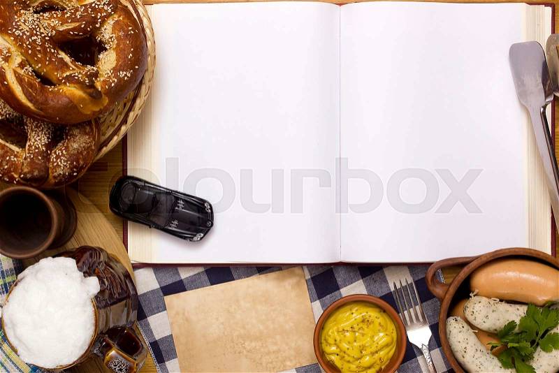 Sausages, pretzels, beer and a book on a wooden table, stock photo