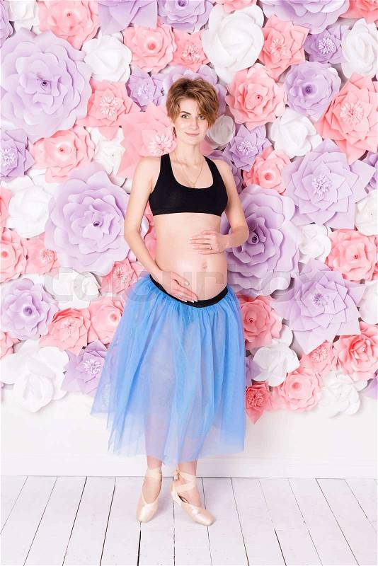 Pregnancy fitness and sport concept happy pregnant woman. Pregnant ballet dancer on flower wall background, stock photo