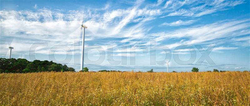 Wind Power Stations in Field with a partly cloudy sky, stock photo