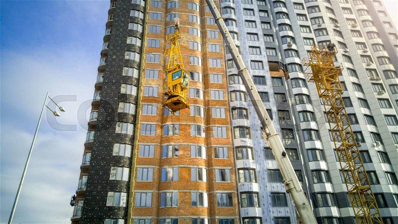 Big industrial crane descend building crane cabin at building site, stock photo