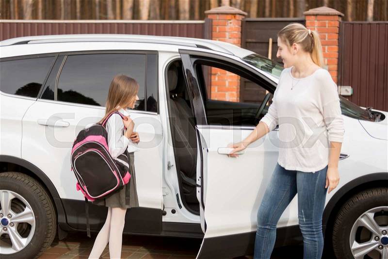 Young mother taking daughter to home after school lessons by car, stock photo