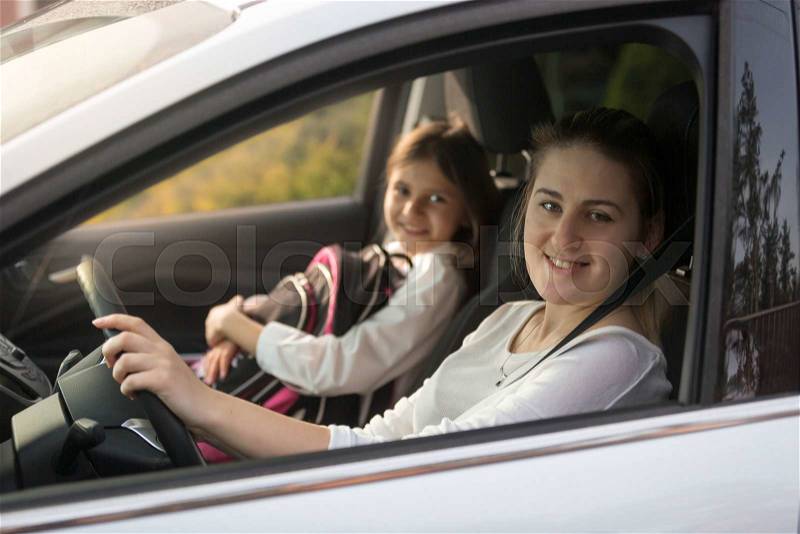 Portrait of beautiful mother driving car with daughter to school, stock photo