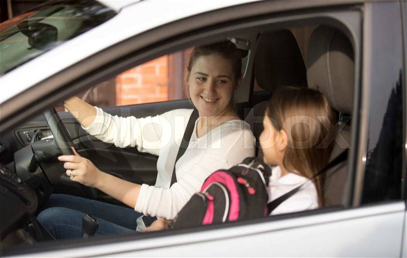 Portrait of young mother driving her daughter to school at morning, stock photo