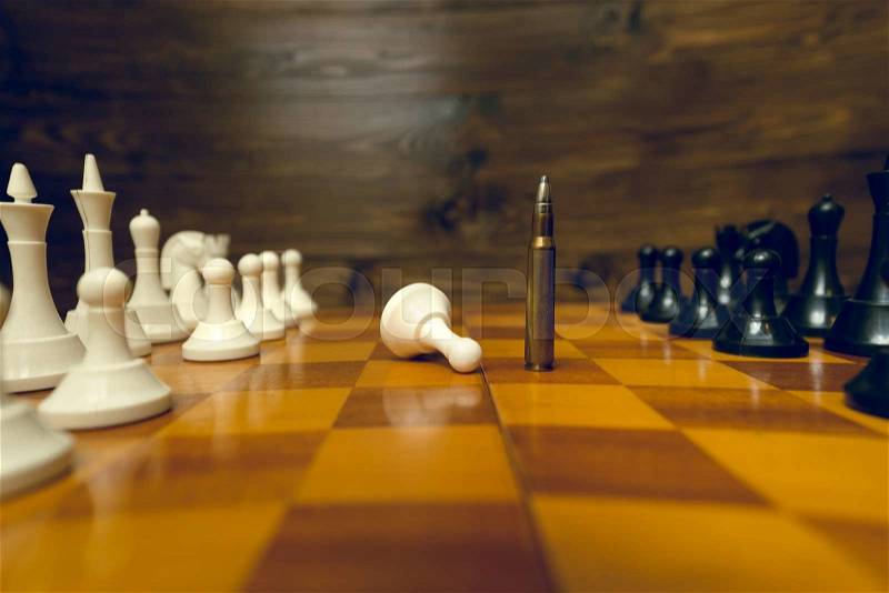 Closeup photo of bullet winning in chess game. Concept of power of guns, stock photo