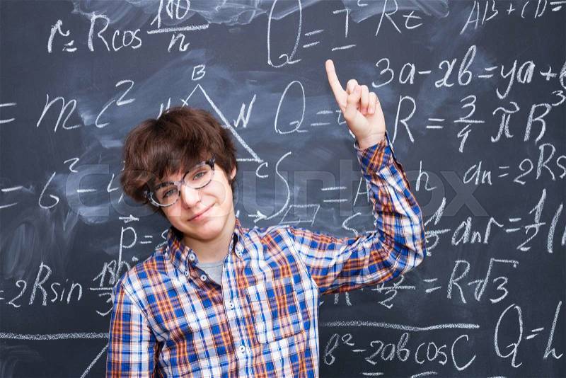 Boy in glasses, blackboard filled with math formulas background, stock photo