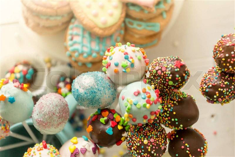 Closeup toned photo of colorful cake pops and cookies with icing, stock photo