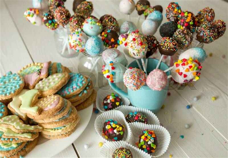 Beautiful decorated cake pops and cookies for Easter on wooden table, stock photo