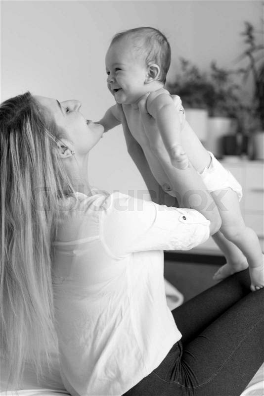 Black and white portrait of happy mother hugging her cheerful baby boy, stock photo