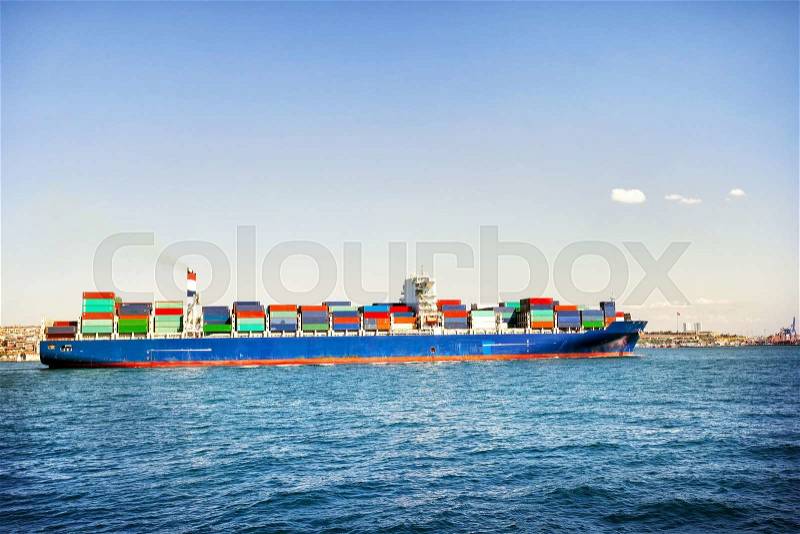 Ship loaded with colorful containers in blue sea, stock photo