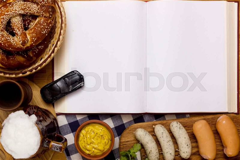 Sausages, pretzels, beer and a book on a wooden table, stock photo