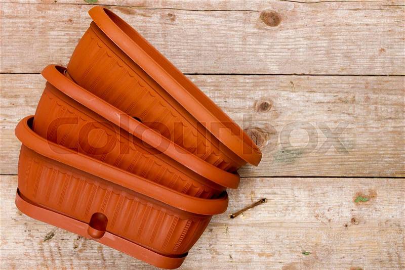 Brown plastic pots for flowers on a wooden background, stock photo