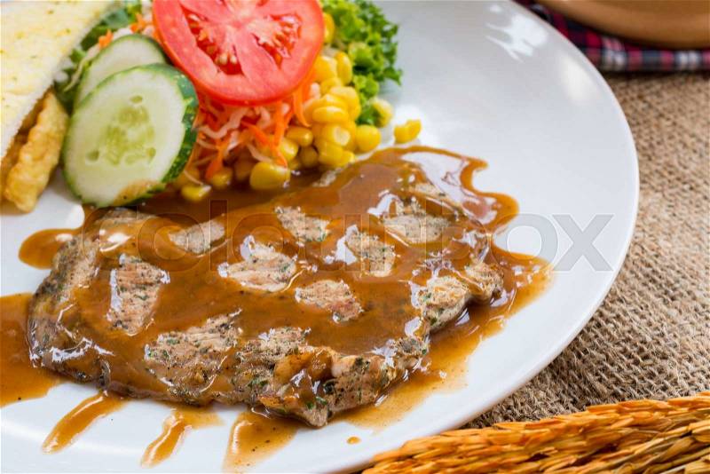 Beef steak with black pepper sauce , salad and French fries on sack background, stock photo