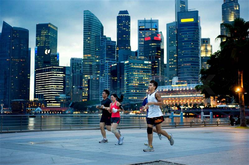 Singapore, Republic of Singapore - May 3, 2011: People running in the evening on embankment in front of business center. Running is very popular sports in Singapore, stock photo