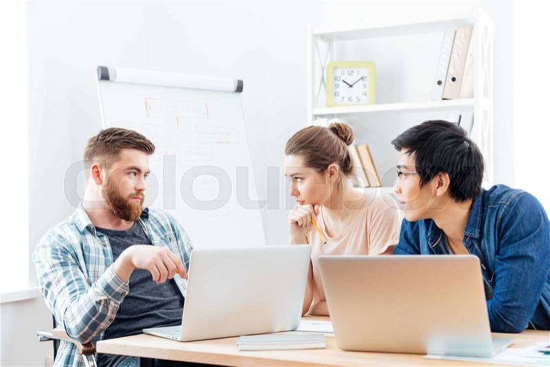 Three serious businesspeople having business meeting in office, stock photo