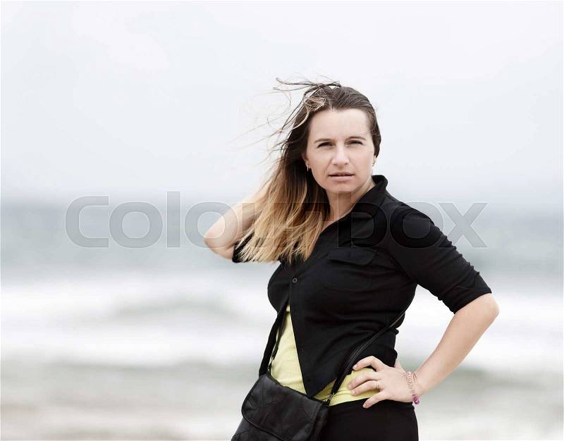 Posing woman outdoors. Long-haired woman. Woman on blurred background of the sea on a windy day. Selective focus on model\'s face, stock photo