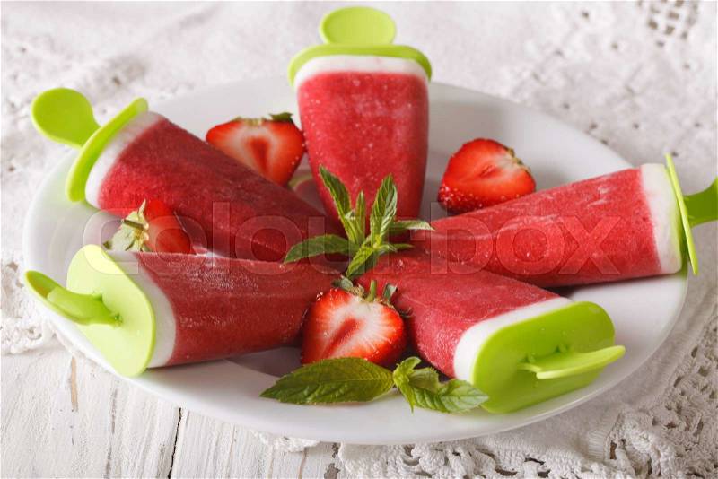 Tasty strawberry sorbet with mint on a stick close up on a plate. horizontal , stock photo