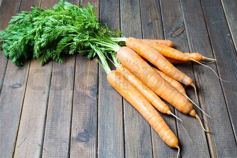 Carrots with fresh green top on wood, stock photo