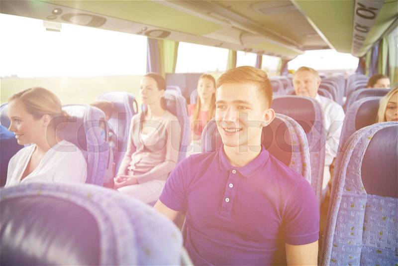Transport, tourism, road trip and people concept - happy young man sitting in travel bus or train, stock photo