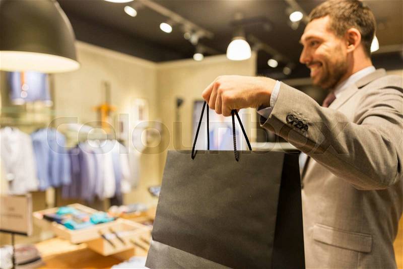 Sale, fashion, retail, business style and people concept - close up of happy man in suit with shopping bags at clothing store, stock photo