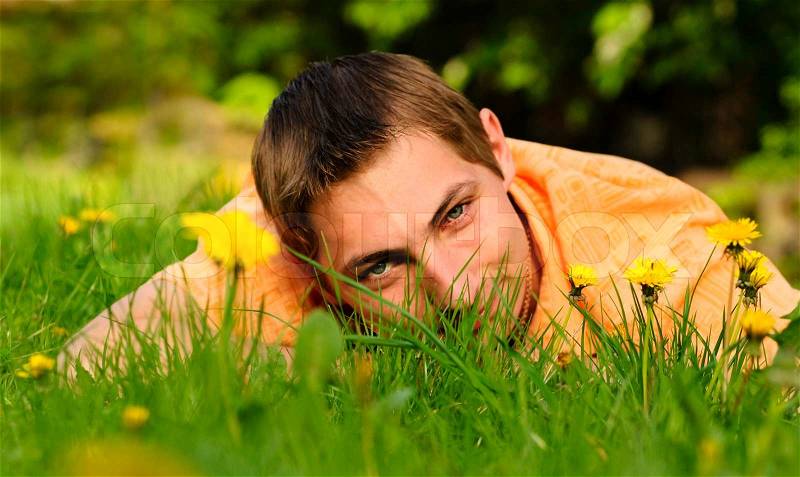 Man lie on the grass. Shallow DOF. Outdoor portrait, stock photo