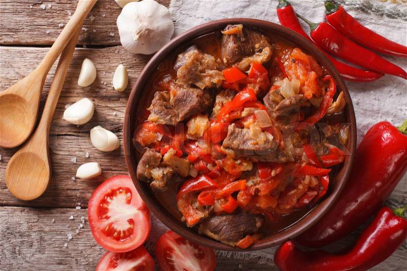Pieces of lamb cooked with onion, tomato and pepper close-up in a bowl on the table. horizontal view from above , stock photo