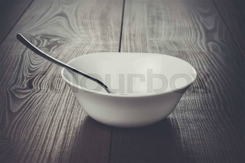 Empty bowl with spoon on brown wooden table, stock photo