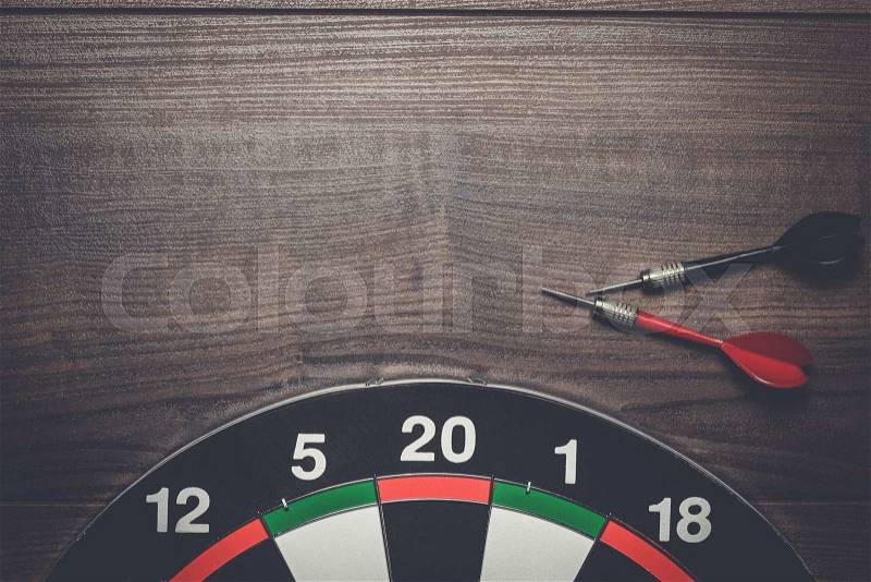 Target and two darts on the brown wooden table, stock photo