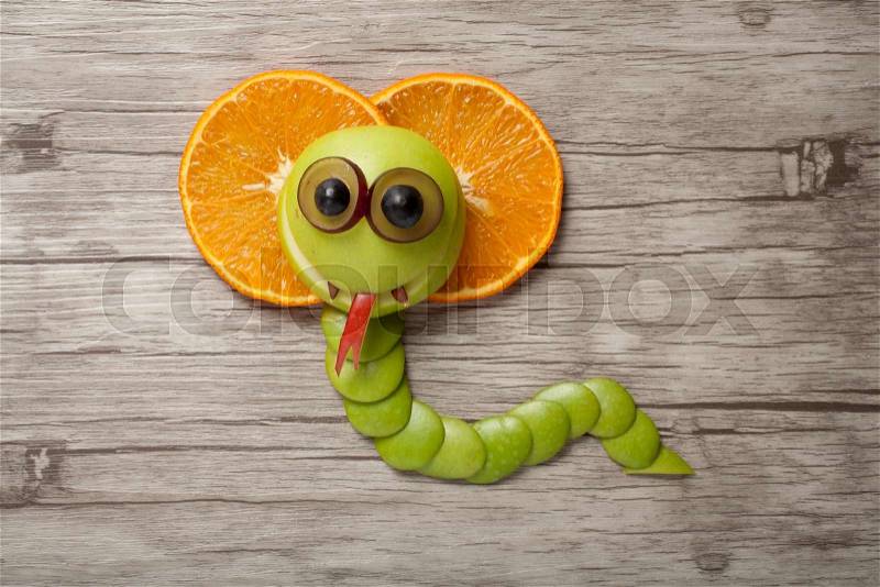Funny fruit cobra made on wooden background, stock photo