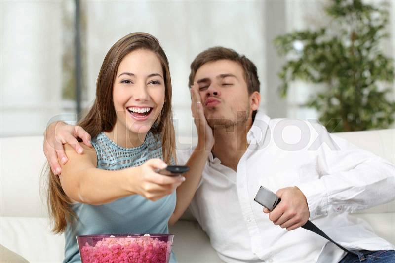 Woman prefers tv instead sex while her husband is trying to seduce her, stock photo