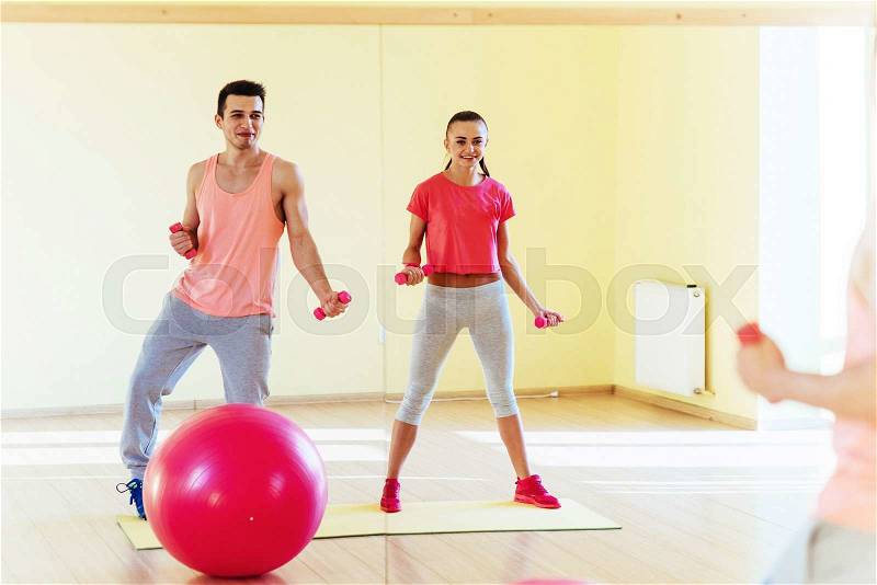 Fitness, sport, training, gym and lifestyle concept - two smiling people working out with dumbbells in the gym, stock photo