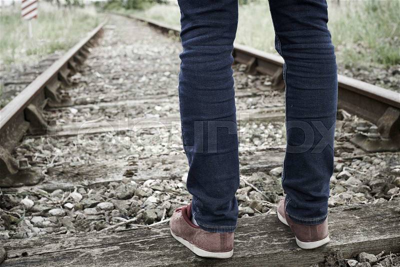 Close-Up Of Man\'s Feet Standing Between Railway Tracks, stock photo