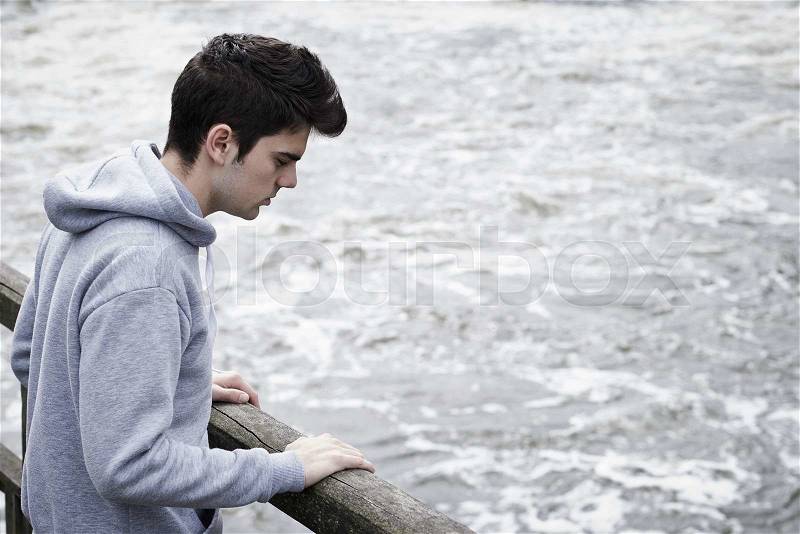 Depressed Young Man Contemplating Suicide On Bridge Over River, stock photo