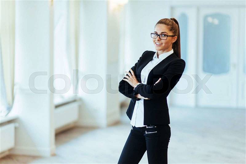 Happy business woman looking confident with modern building as background, stock photo