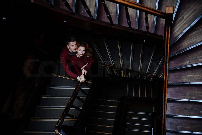 A couple of young people on the wooden stairs in the entrance of an old house, stock photo