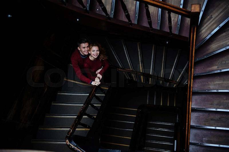 A couple of young people on the wooden stairs in the entrance of an old house, stock photo