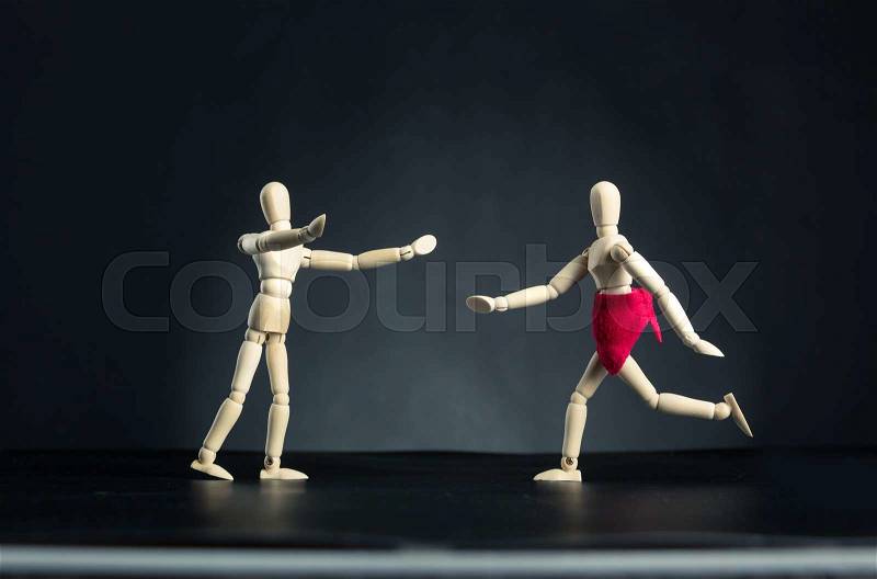 Wooden carved figures, woman running to man over black, stock photo
